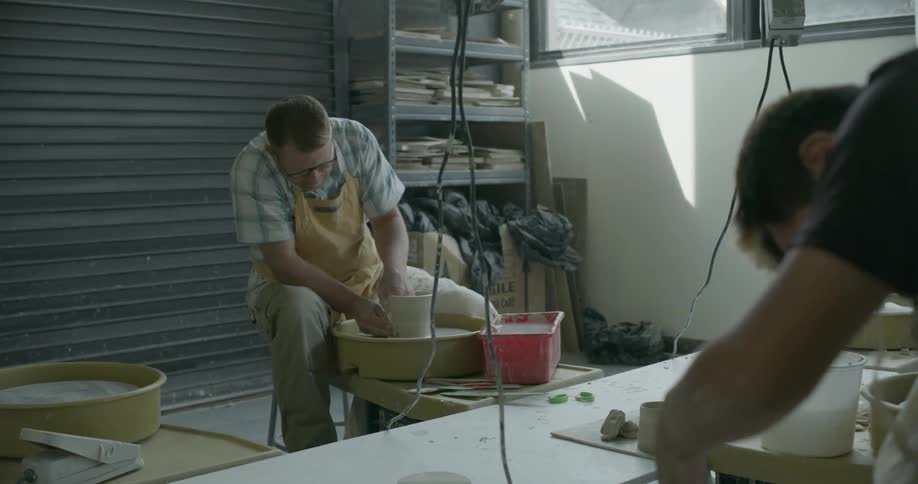 A couple of men are shaping pottery
