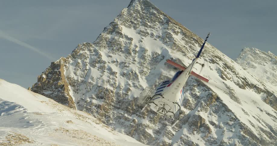 A helicopter flies high over the mountain