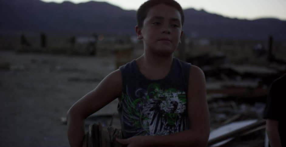 Child carries kindling away from a large pile