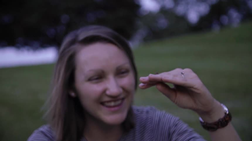 Woman smiles while holding a firefly