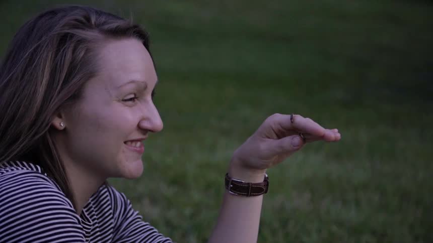Woman smiles at firefly resting on her hand