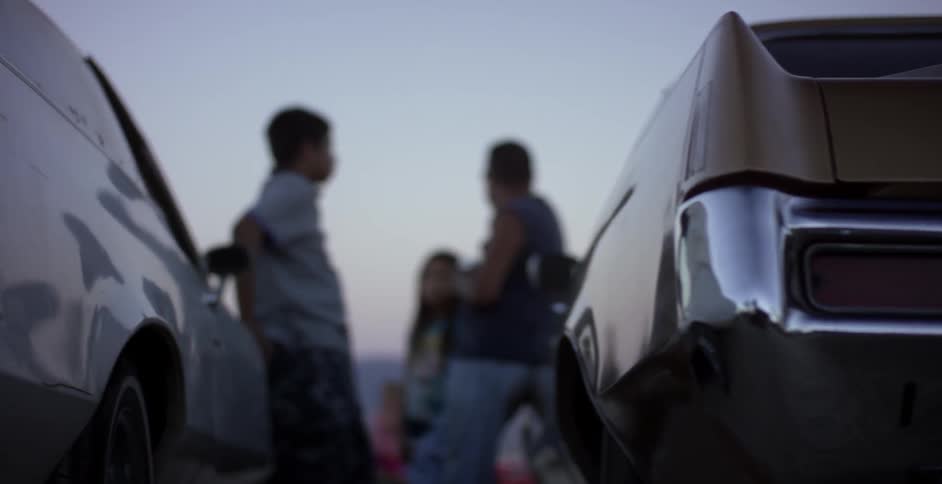 People stand outside between two cars