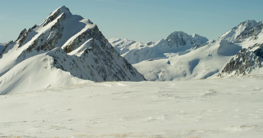 Snow covers mountain peaks and slopes on a sunny day