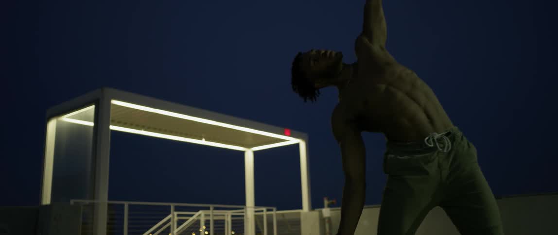 A man is dancing on a parking garage rooftop at night