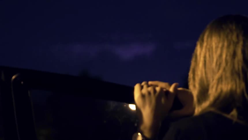 Woman watches lightning storm at night