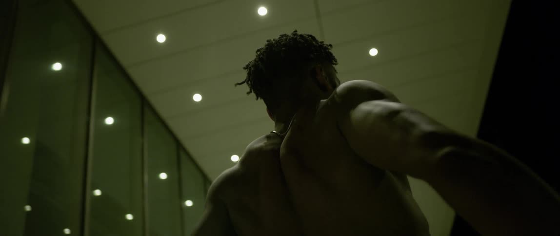 A man is dancing outside beneath a roof in the city at night