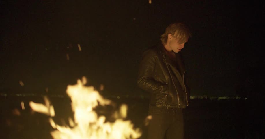 Man stands next to bonfire at night