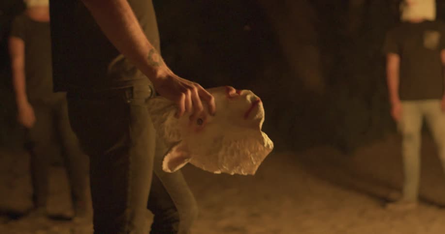 People stand around a campfire with sheep masks