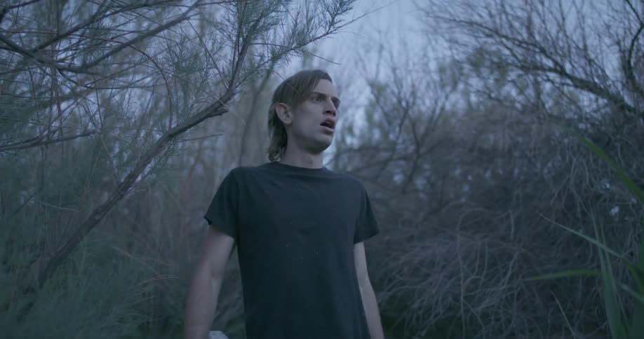 A man running in a natural landscape stops and stares ahead of him