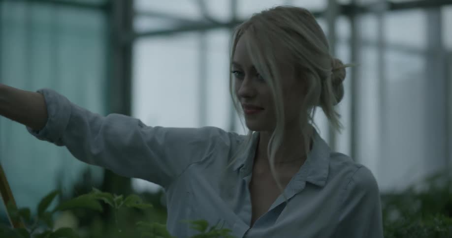 Woman waters plants in a greenhouse