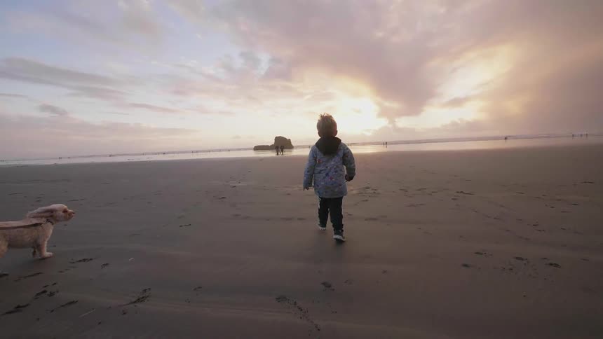 Young child runs on a beach at sunset