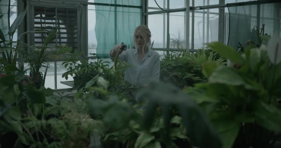 Woman waters plants in a greenhouse