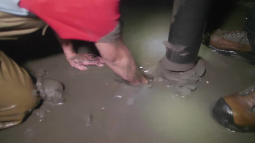 People kneeling down and digging in sand at night