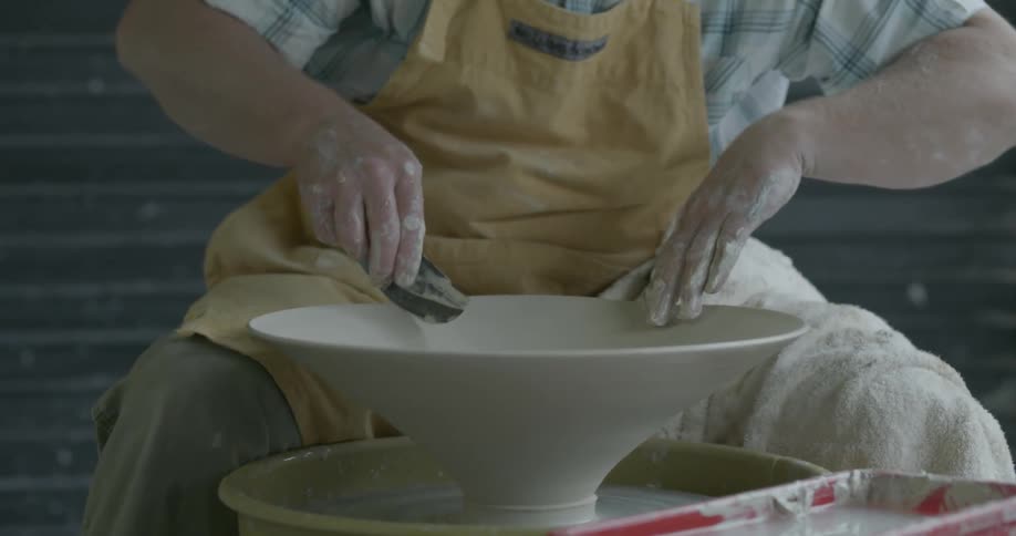 Man shapes clay on a pottery wheel