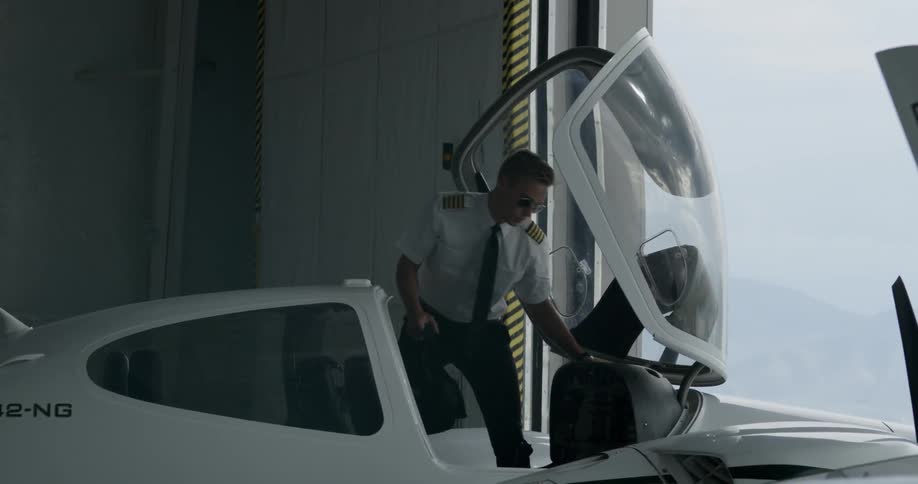 Pilot getting into small aircraft in hanger