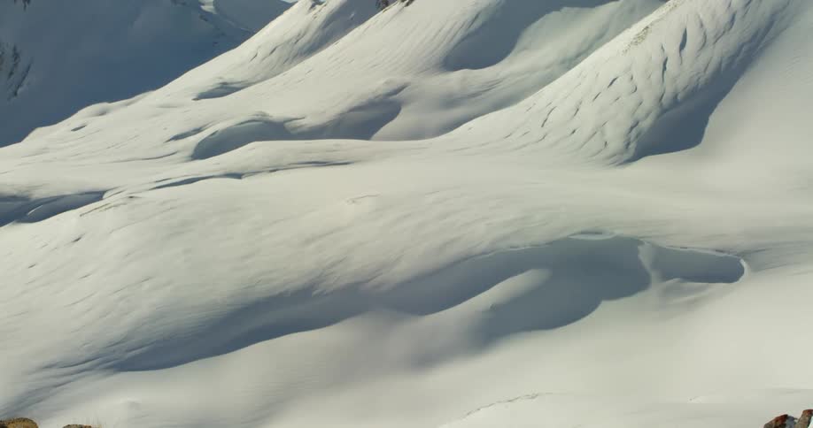 Mountain slopes and rocks are covered in snow