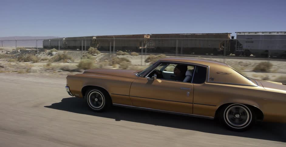 A person drives a classic car through the desert