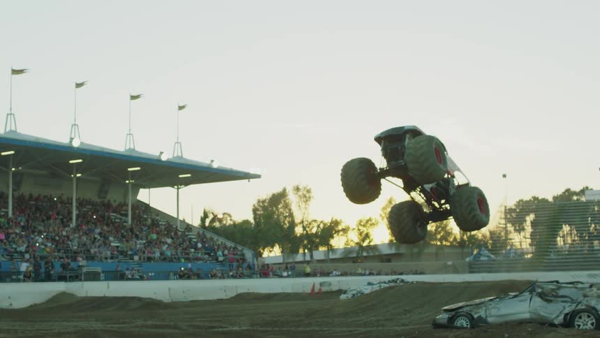 A crowd is watching a monster truck performance in a stadium