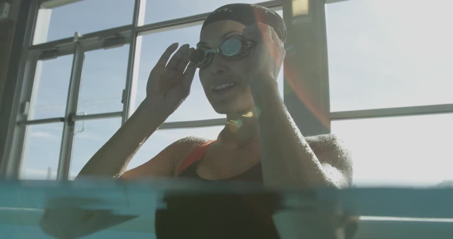Woman placing her water goggles while standing in a pool