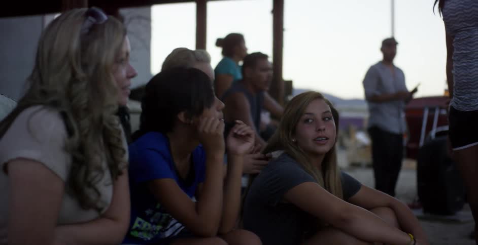 Group of people sit near a truck as they chat