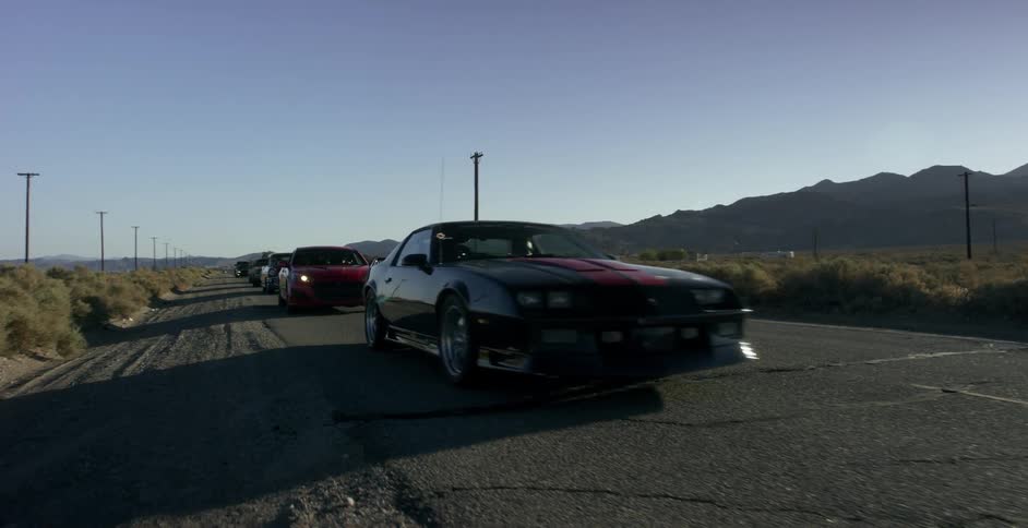 A row of cars are moving down the road