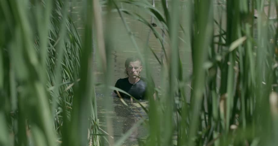 Man swims through marsh in his street clothes