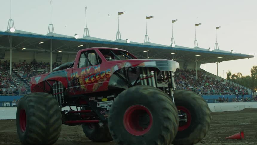 An audience watches a monster truck in a stadium