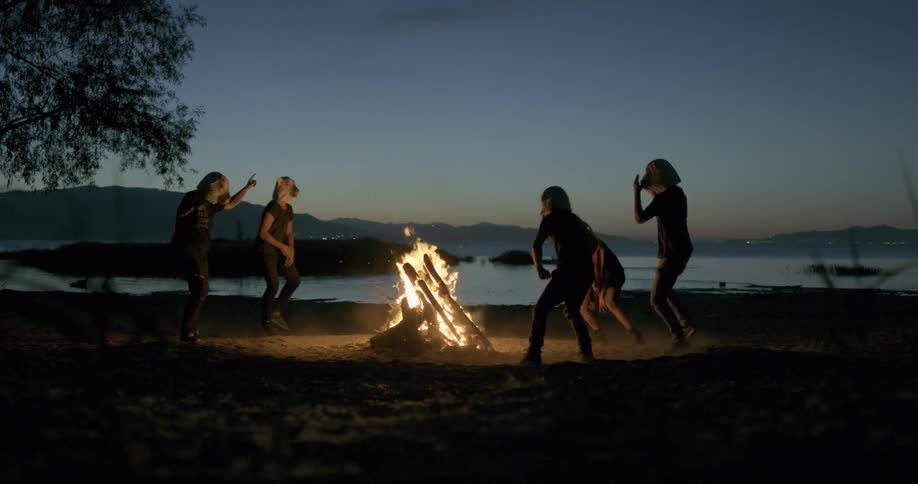 Men in sheep masks dance around bonfire