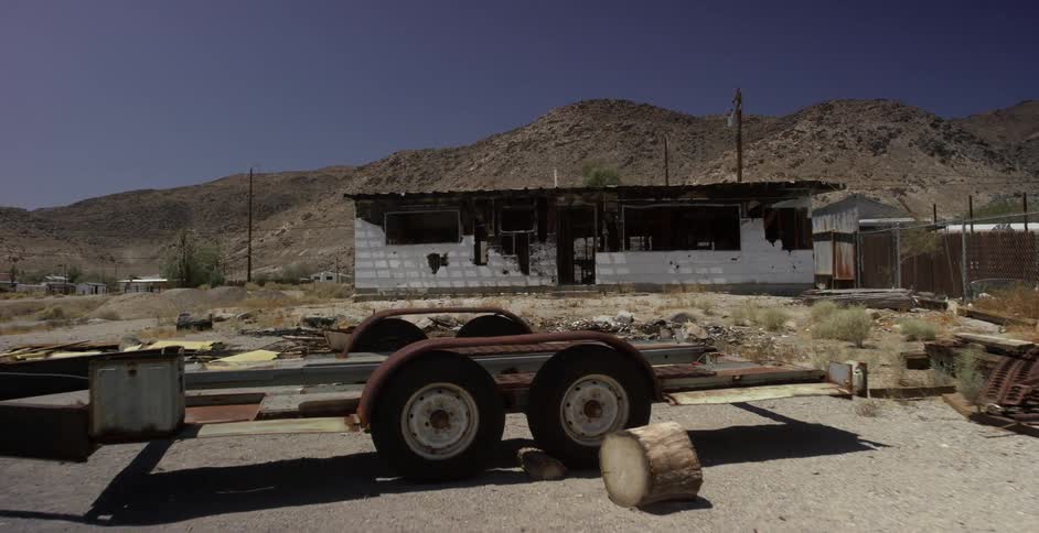 Trailers sit in a parking area in front of an abandoned house