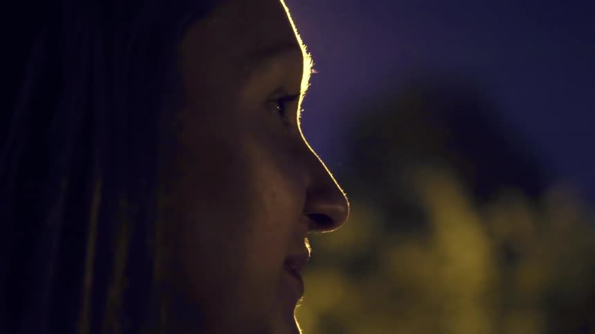 A woman smiles as she stands outside at night