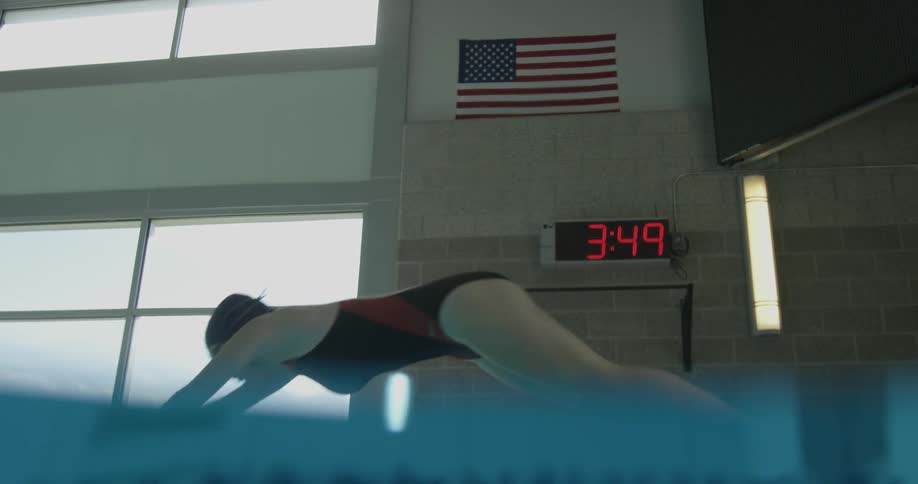 A woman dives into the pool as the clock turns