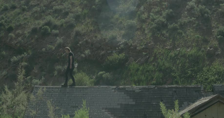 A man is walking along the top of a roof on a house