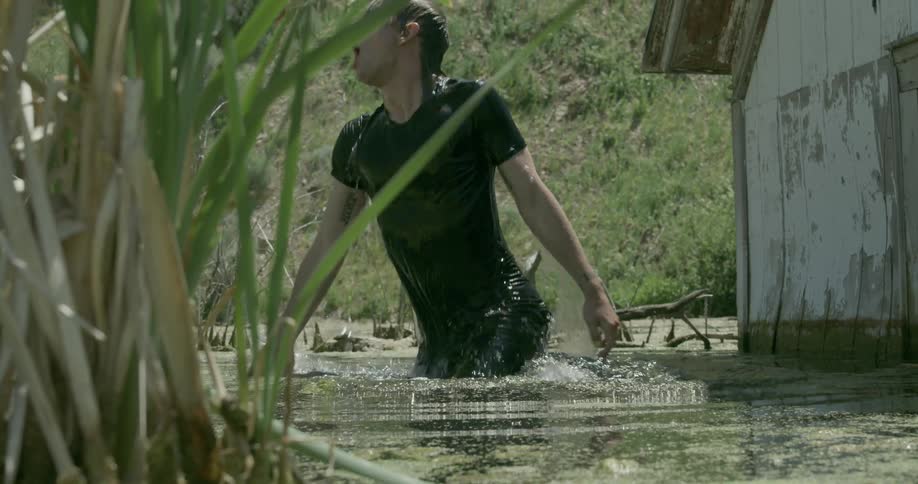 Man coming up from under water in swamp