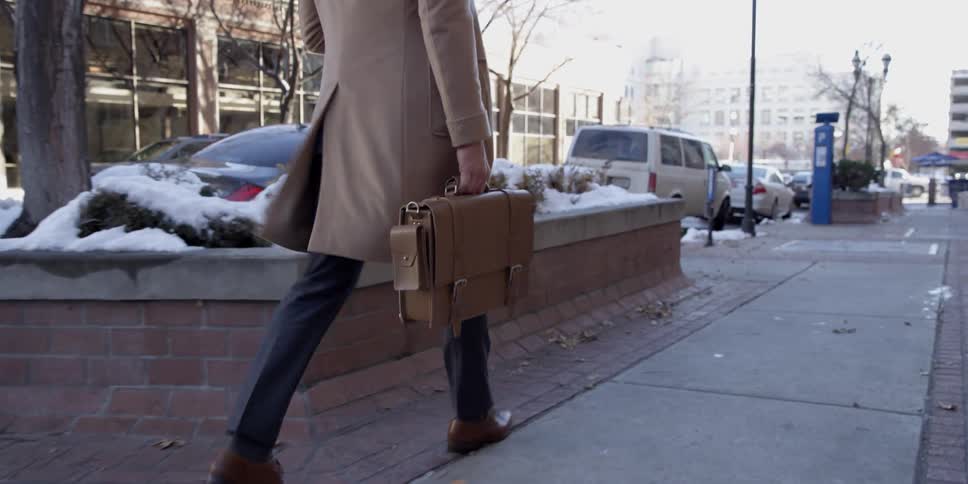 Man walks with briefcase on city sidewalk