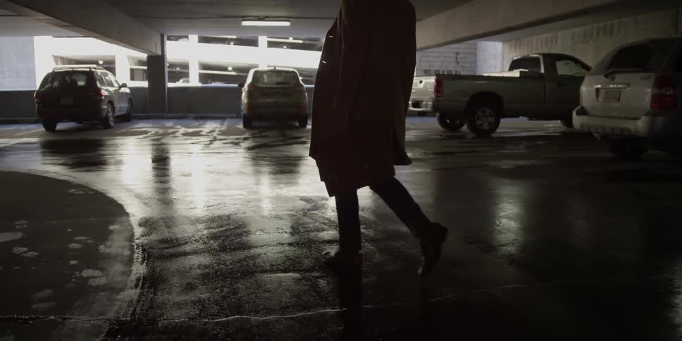 A person is walking through the parking lot with a bag