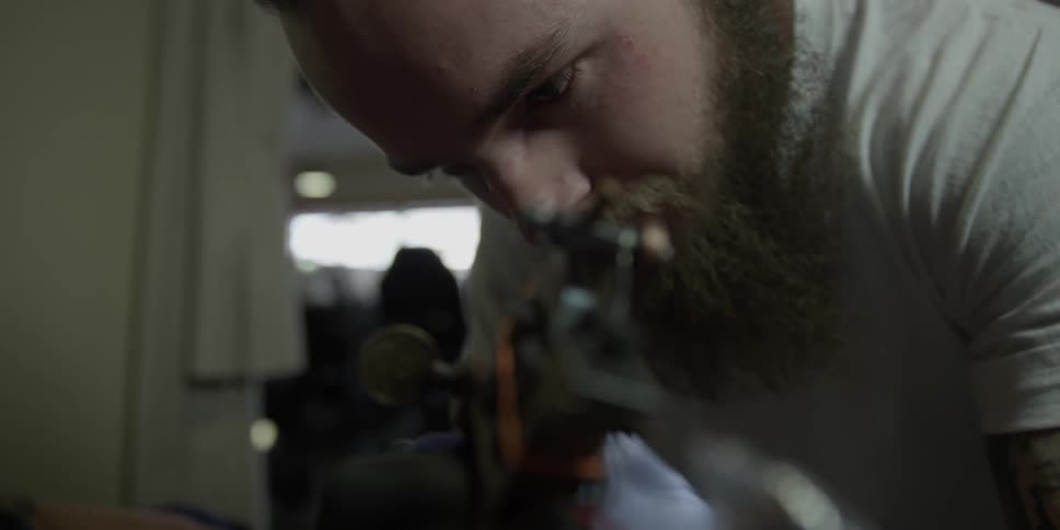 A tattoo artist works with a needle