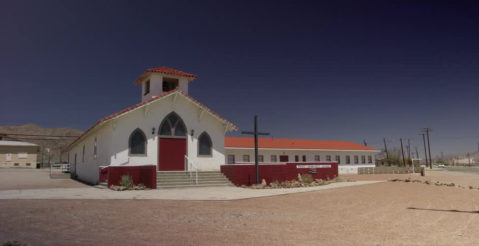 A large cross stands in front of a rural church