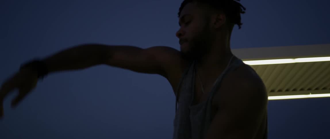 A man is dancing and swinging his arms at night