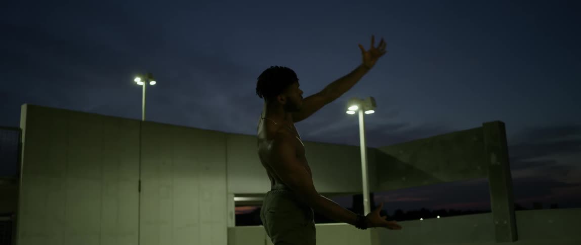 A man is dancing on a parking garage rooftop at night