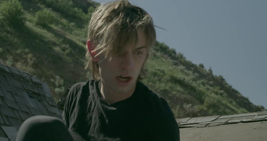 A man removes his mask and gets up on the roof