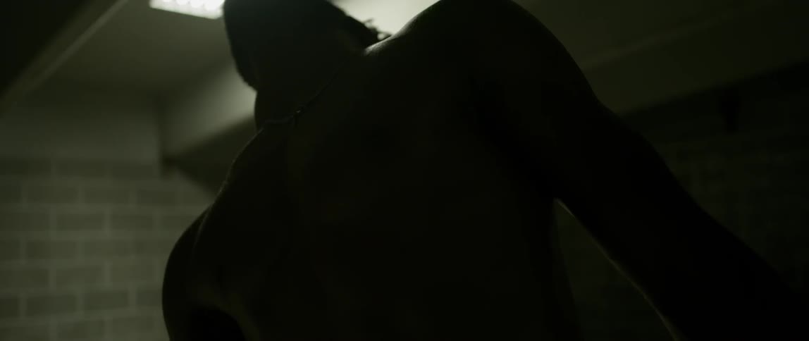 A man arches his back as he dances in a brick building