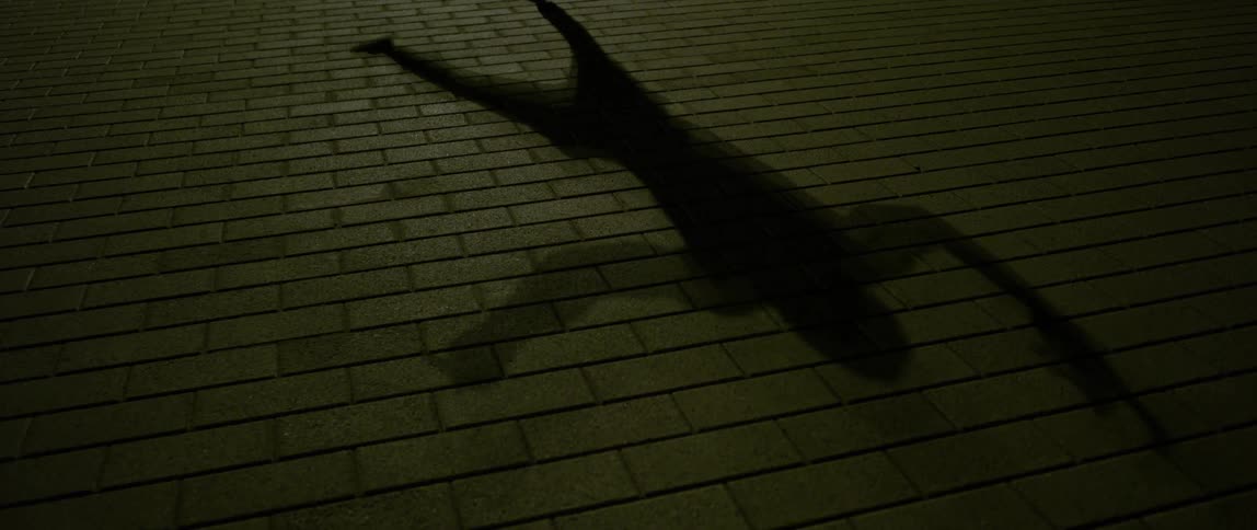 A shadow of a man dancing is on the sidewalk