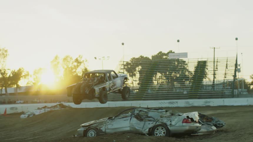 A monster truck jumps over some crushed cars