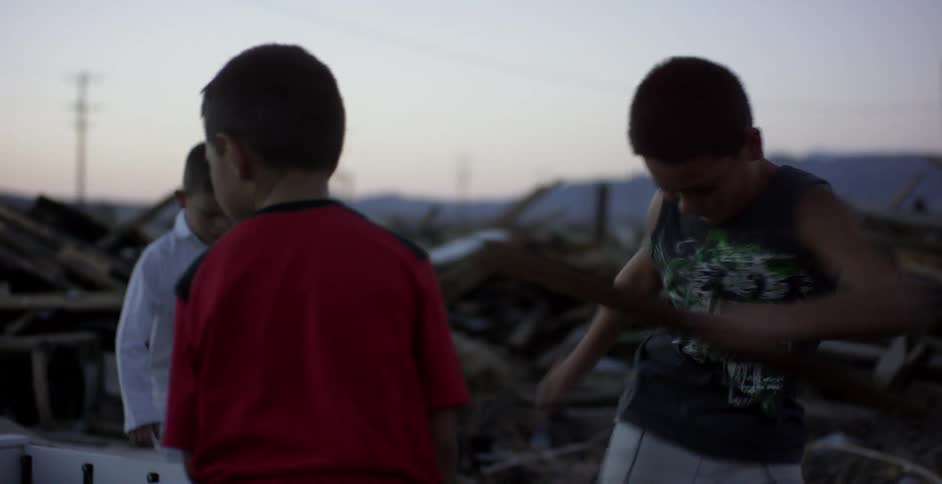 Boys stomp on wood near piles of debris