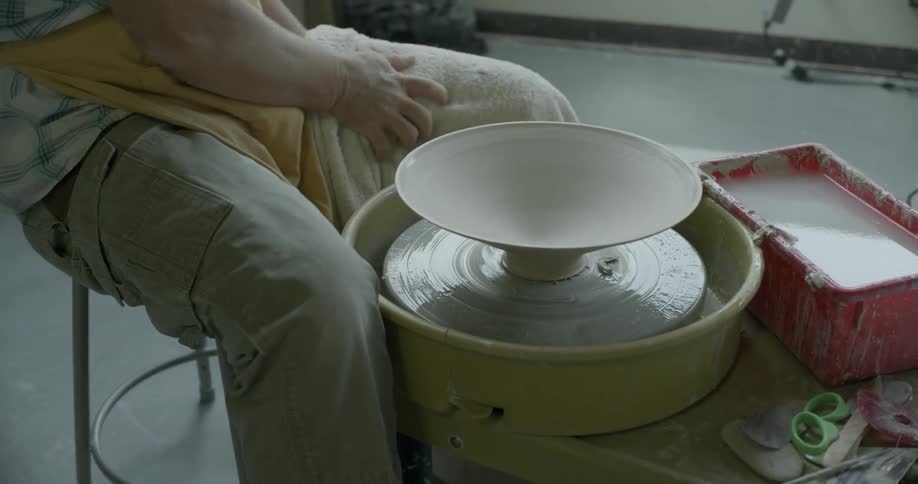An artisan crafting a bowl removes it from the pottery wheel