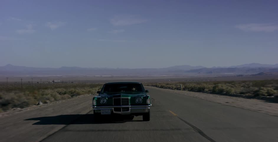 A green car driving a country road