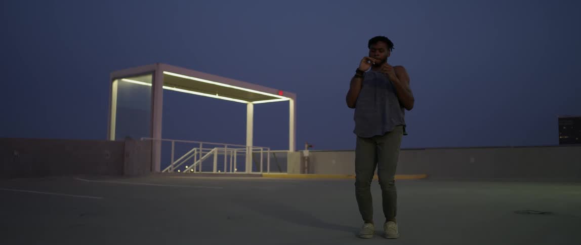 Man dances on top level of a parking garage