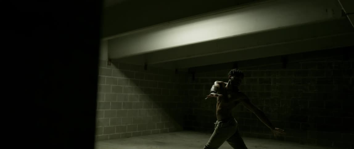 A man is stretching and exercising in the dark garage