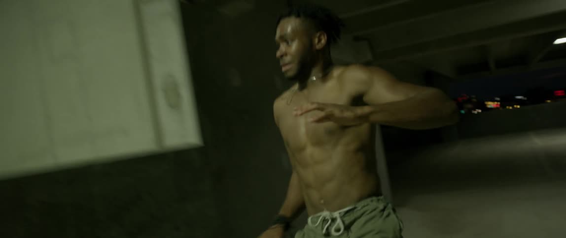 A man without a shirt is running through a parking garage