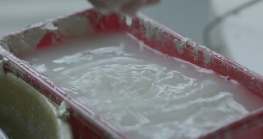 A worker washes an object in murky water
